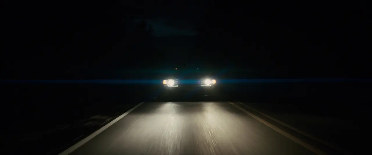 Headlights approaching on a dark road, a visual reference for Keep Driving