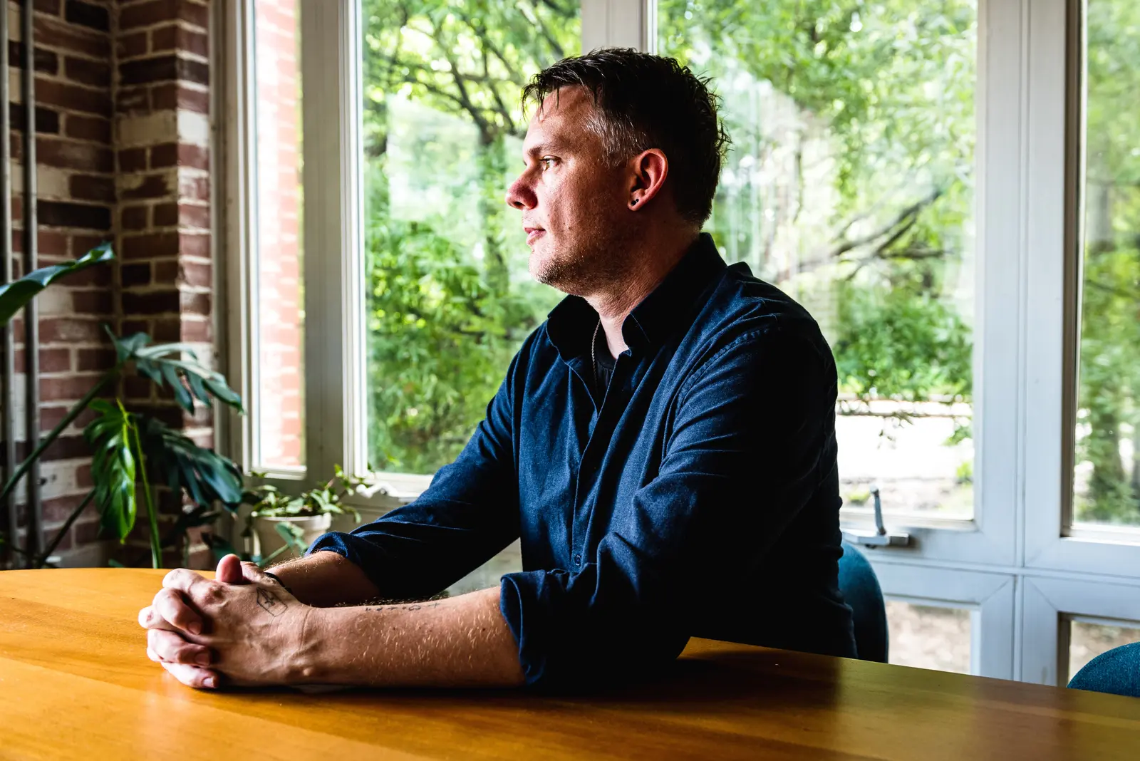 Christopher Shank seated at a table beside a large window.